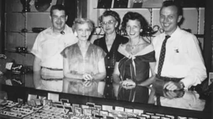 A group of people standing in front of a jewelry store.