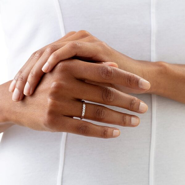 A woman's hands holding a diamond band ring.