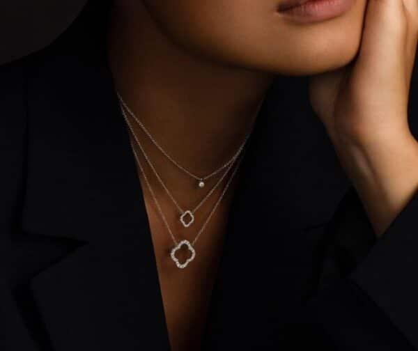 A woman wearing a black jacket and a necklace with diamonds.