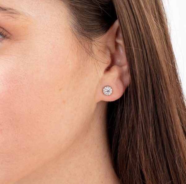 A woman's ear with a diamond stud earring.