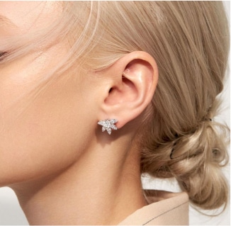 A woman wearing a pair of earrings with diamonds.