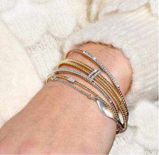A woman's wrist with several gold and diamond bracelets.