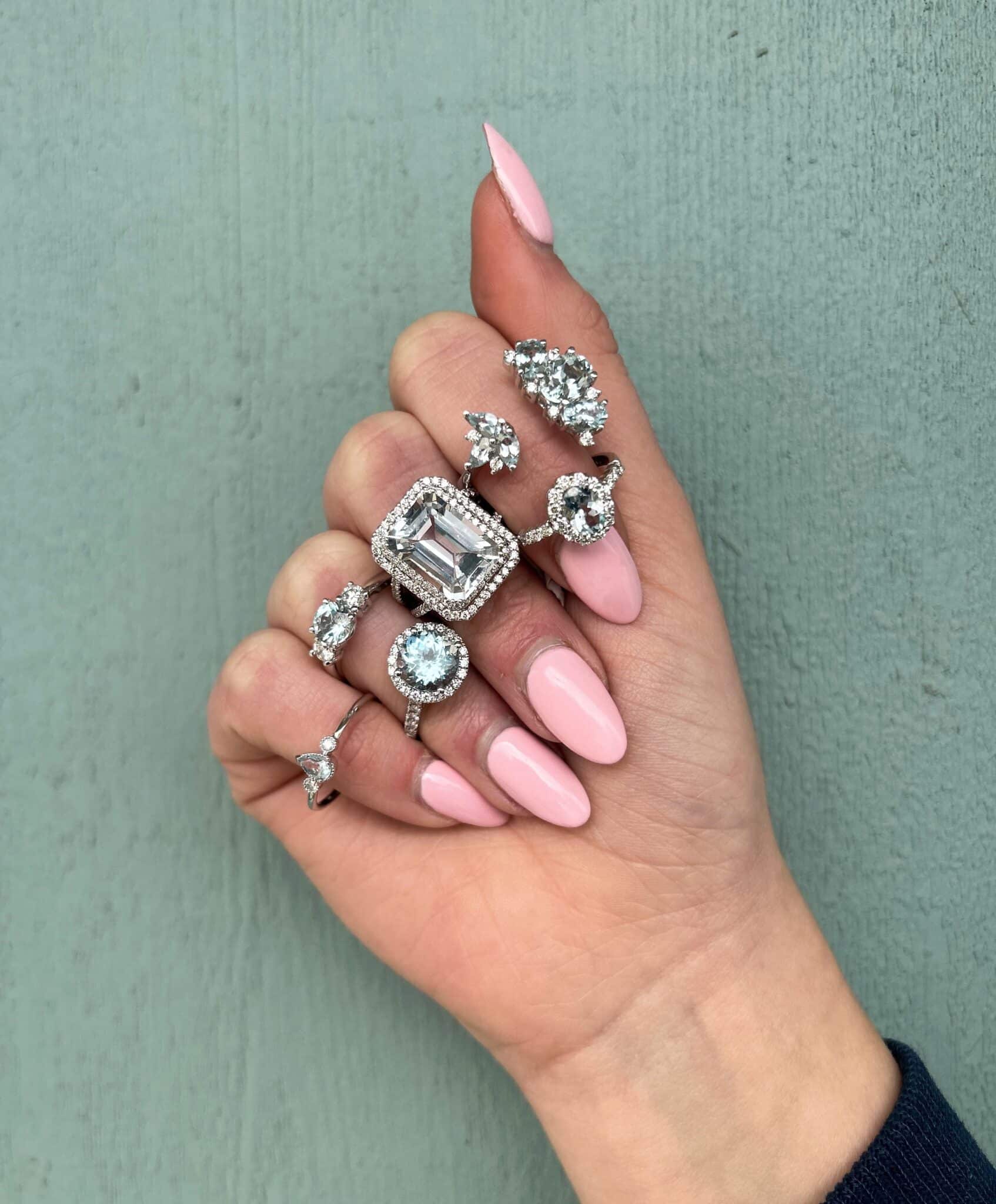 Woman's hand with six different aquamarine rings on her fingers.